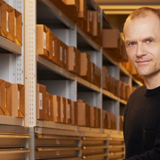 Adam Jon Kronegh ved siden af reoler med arkivkasser