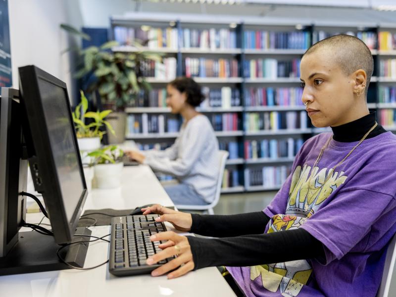studerende sidder ved computer på biblioteket